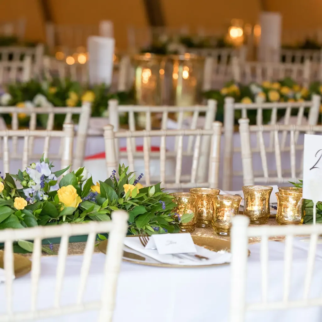 Trestle tables with white chivari chairs and yellow roses