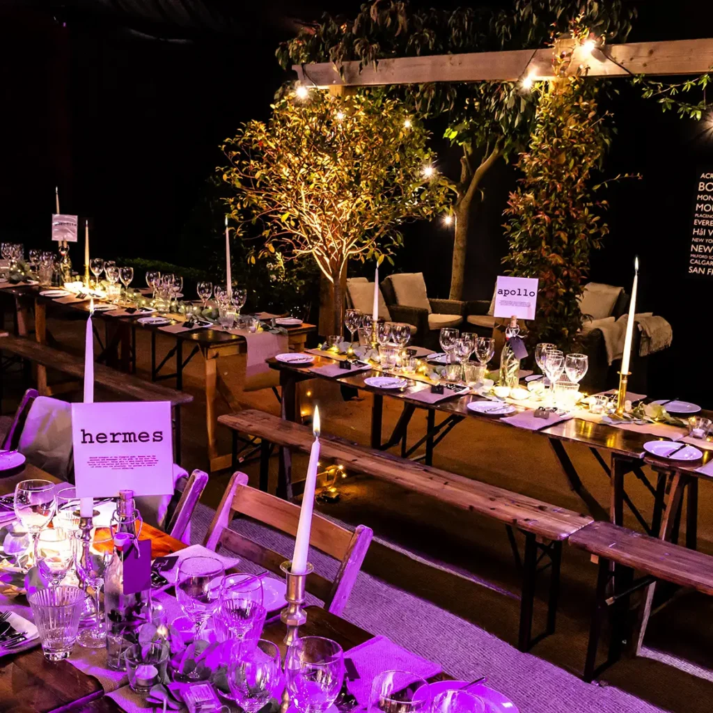Trestle tables decorated with candles and Greek Gods for tale names
