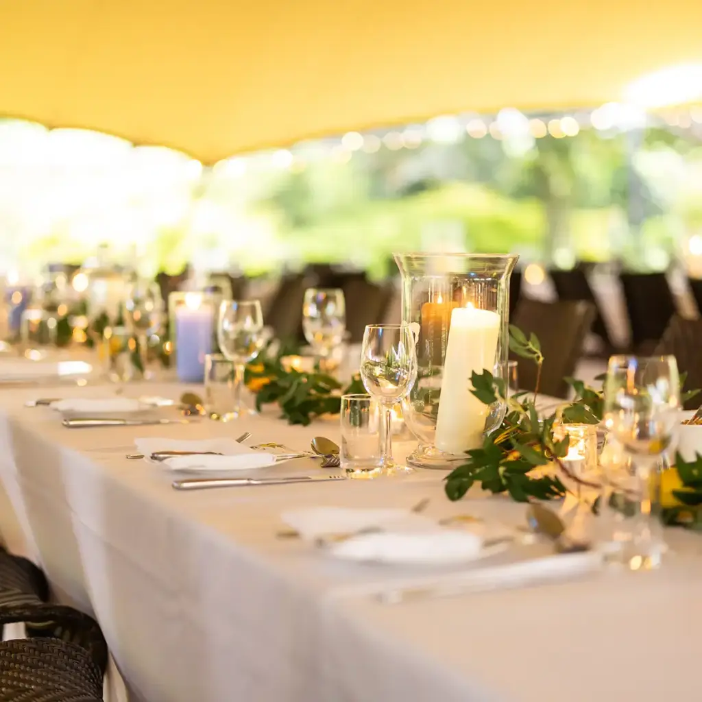 Trestle tables with white table clothes in stretch tent with lemons and olive branches as decor