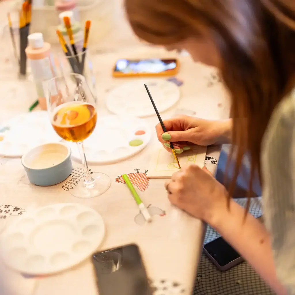 A guest paints a tile with wine on table