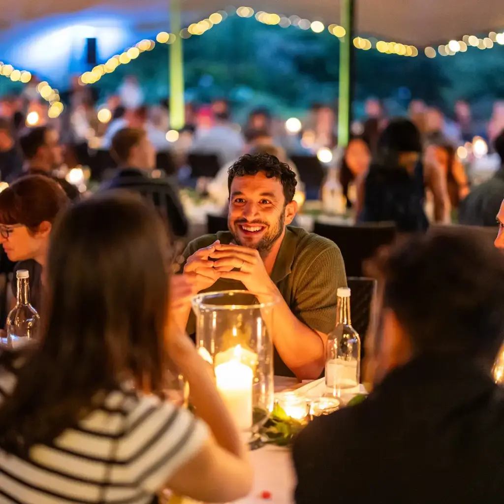 Guests eating in stretch tent marquee by candlelight